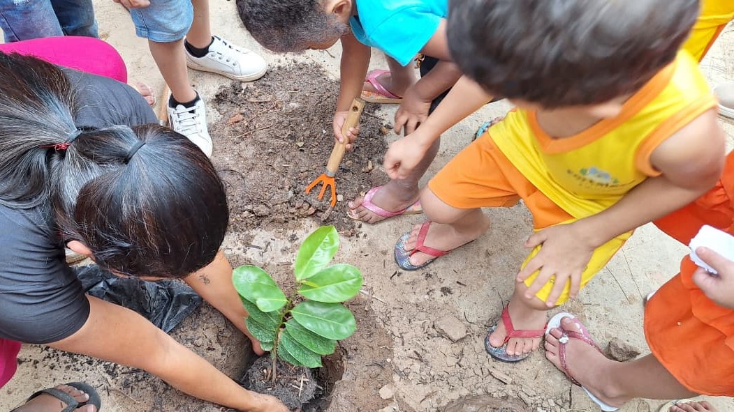 uma professora e uma criança plantando uma muda